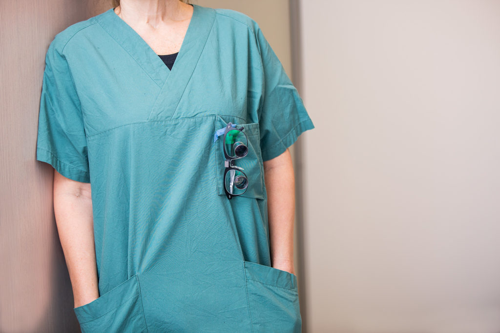 Kvinnelig kirurg i grønn operasjonsskjorte. Foto